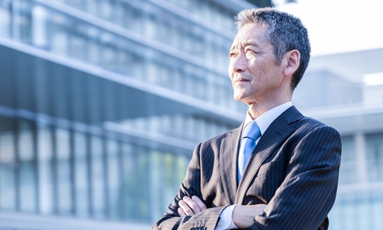腕を組むスーツ姿の男性